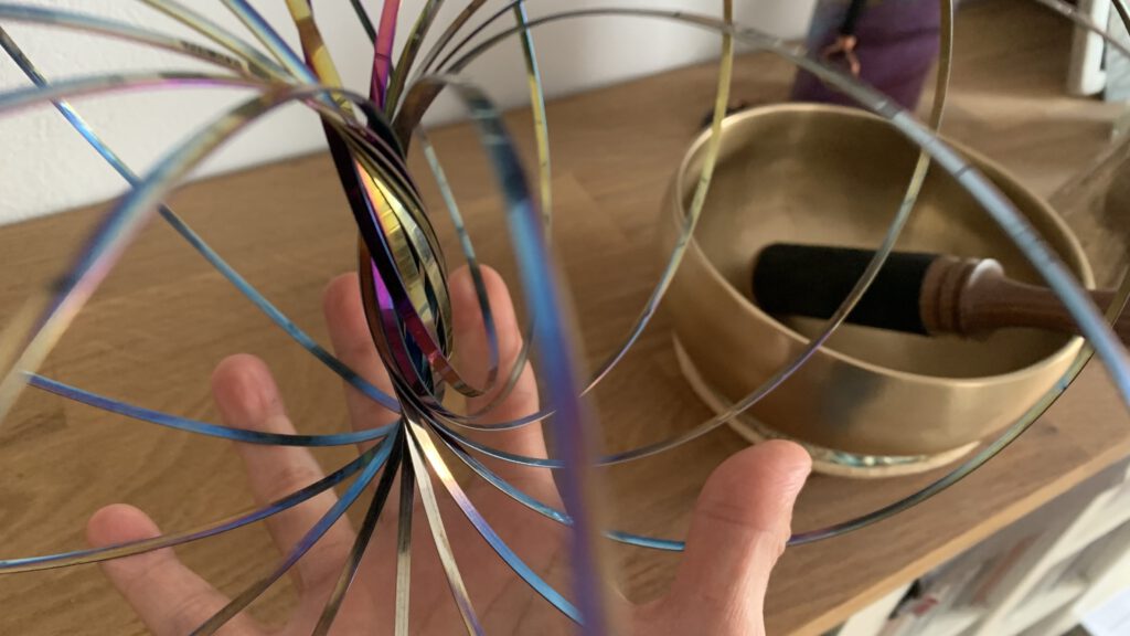 Eine Hand, die einen Torus hält, links daneben angeschnitten eine Klangschale für die Energiearbeit