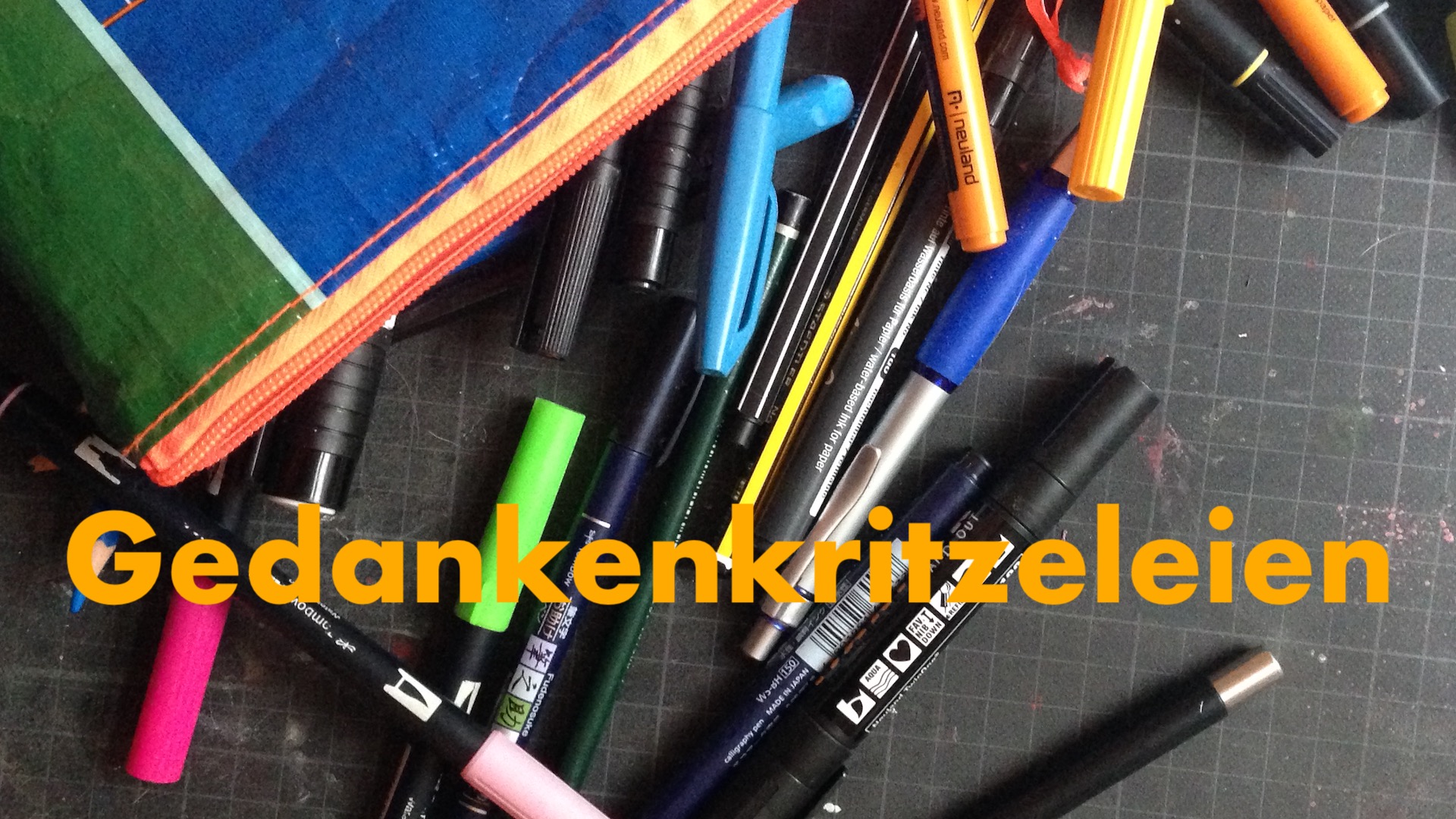 Bildausschnitt, bunte Federmappe mit ausgekippten Stiften auf einer schwarzen Schneidematte