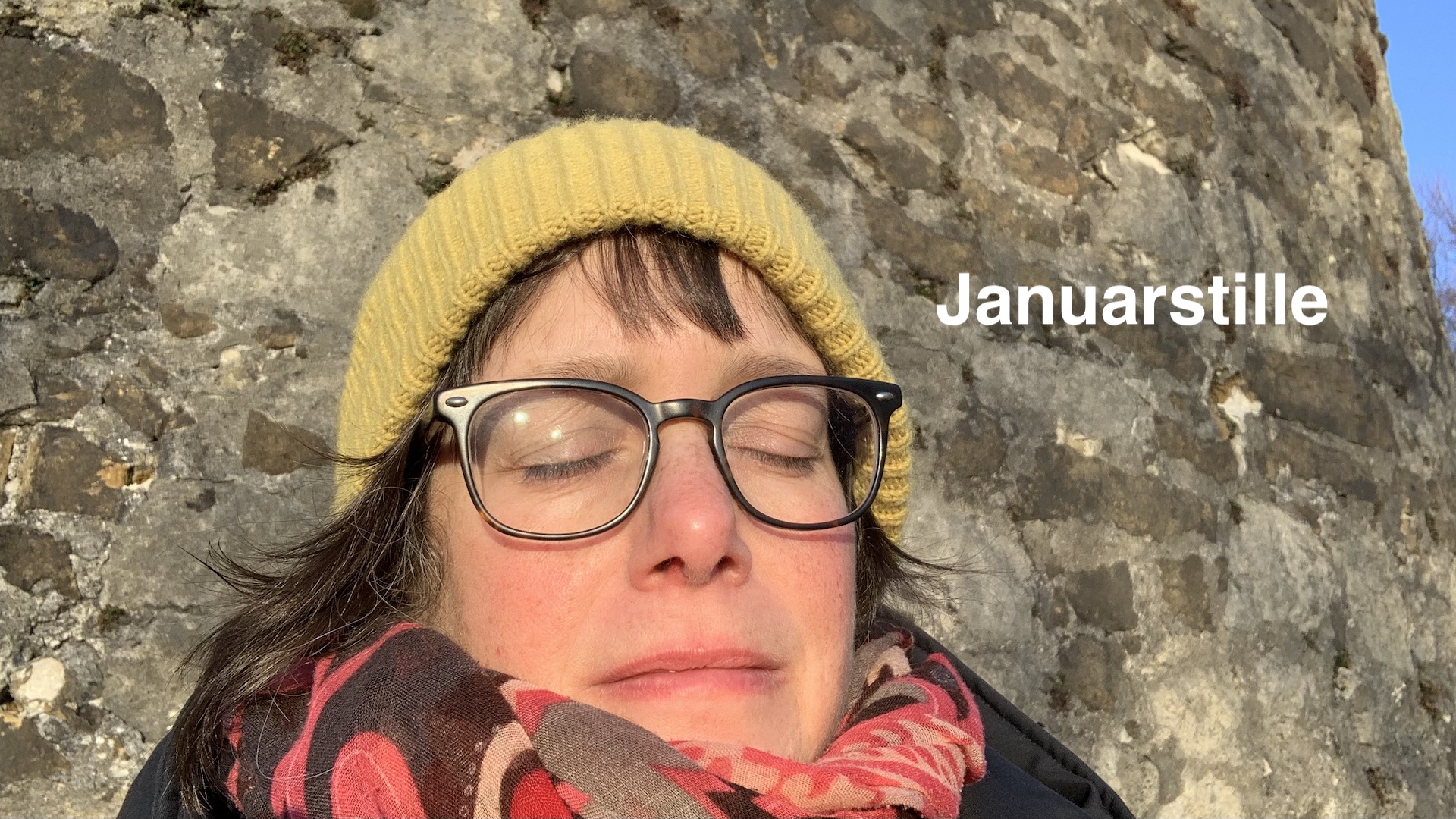 Portrait Katja Reetz, mit Geber Mütze und geschlossenen Augen vor einer Kalksteinwand