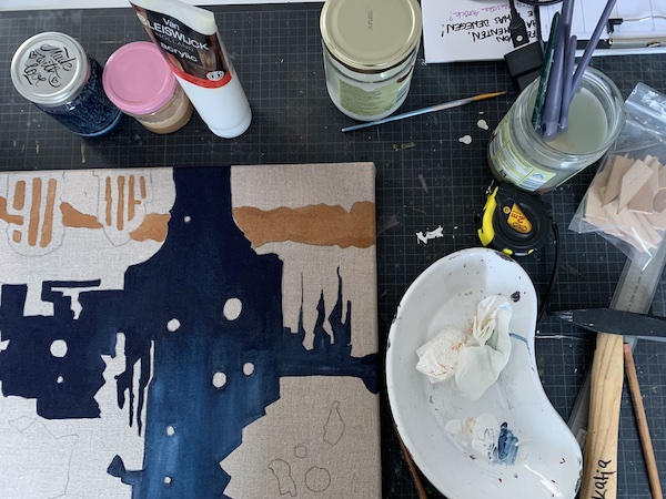 Stillleben bestehend aus Leinwand, Gläsern mit angemischter Farbe, einem Glas mit Pinseln, einem Hammer, einer Palette.