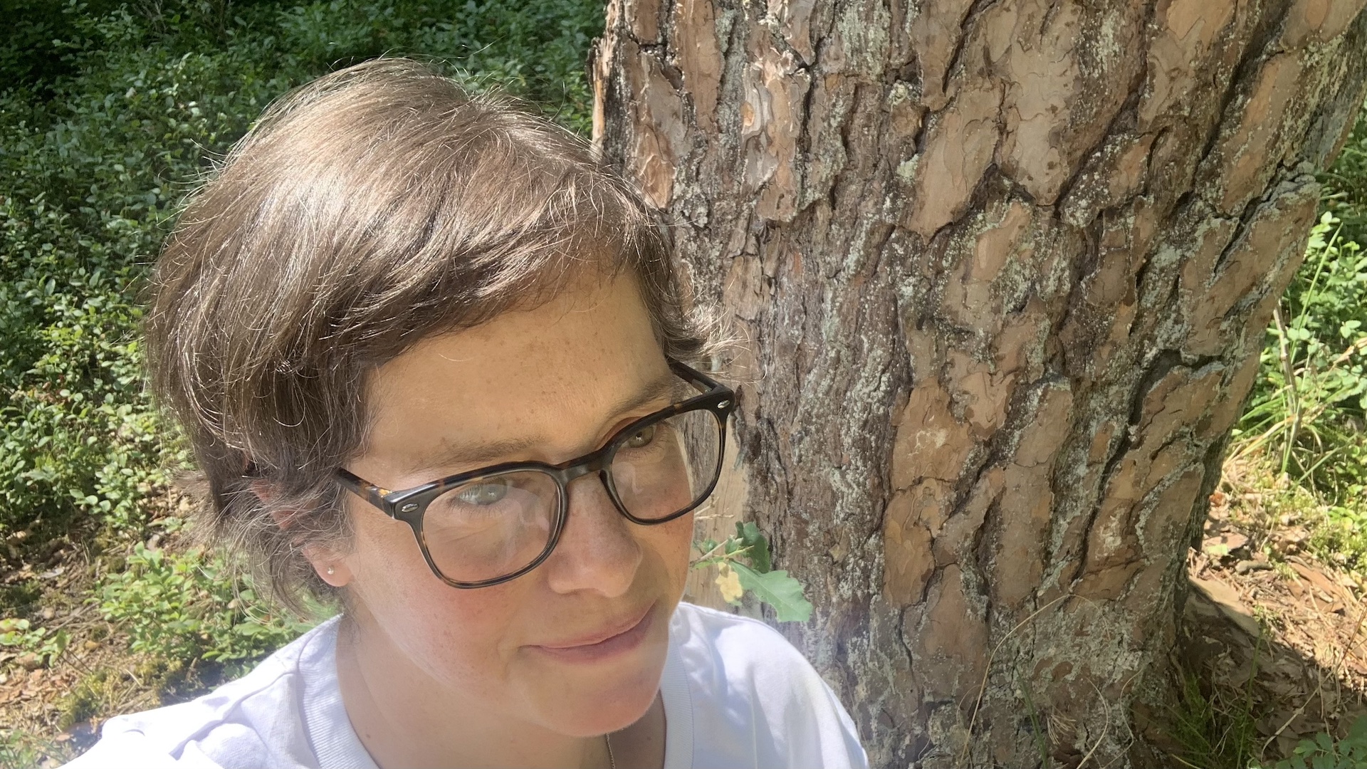Porträt von Katja Reetz mit freundlichem, klarem Gesichtsausdruck, aufgenommen aus einer leichten Vogelperspektive in einem dichten Wald.