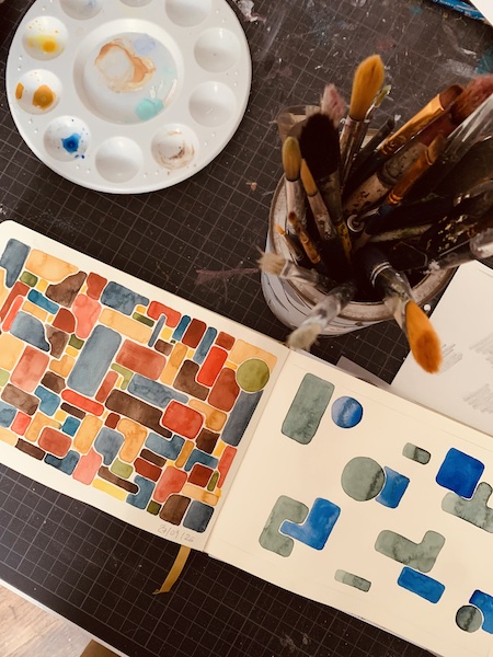 Stillleben mit Palette, Skizzenbuch und Pinseldose von oben fotografiert.
